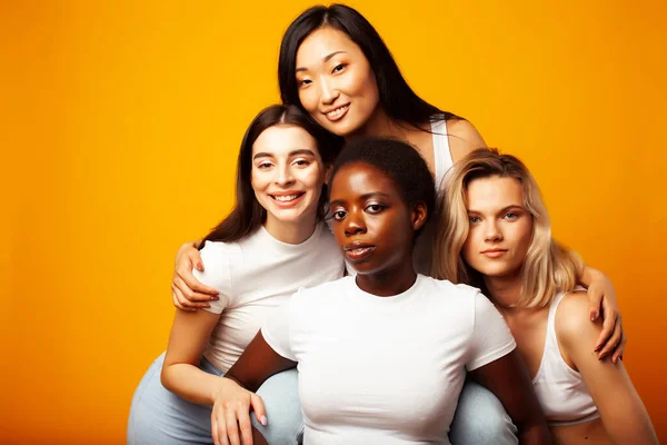 diverse multi nation girls group, teenage friends company cheerful having fun, happy smiling, cute posing on yellow background, lifestyle people concept, african-american, asian and caucasian