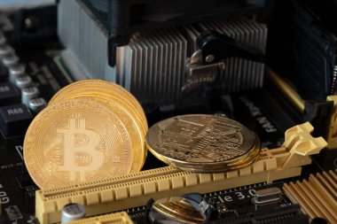 Bilgisayar panosundaki altın bitcoin 'ler. Ana kart arka planında şifreli para birimleri.