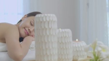 Genç bir Asyalı kadın tatil sırasında masaj masasında spa 'da uzanıyor. İnsanlar otelde tatil sırasında bir kıza el masajı yapıyor..