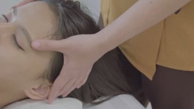 Genç bir Asyalı kadın tatil sırasında masaj masasında spa 'da uzanıyor. İnsanlar otelde tatil sırasında bir kıza el masajı yapıyor..