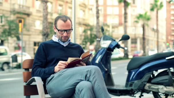 Man reading book on bench — Stock Video