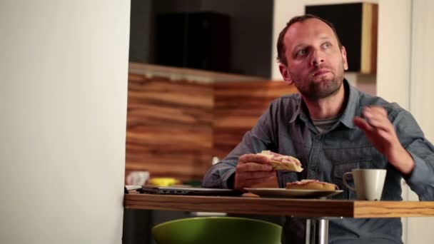 Человек ест сэндвич и пьет чай — стоковое видео