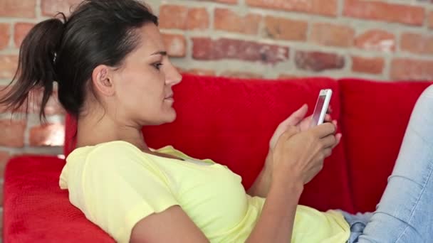Mujer con Smartphone en el sofá — Vídeos de Stock