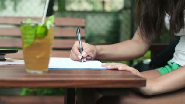 Estudiante escribiendo en cuaderno en la cafetería — Vídeo de stock