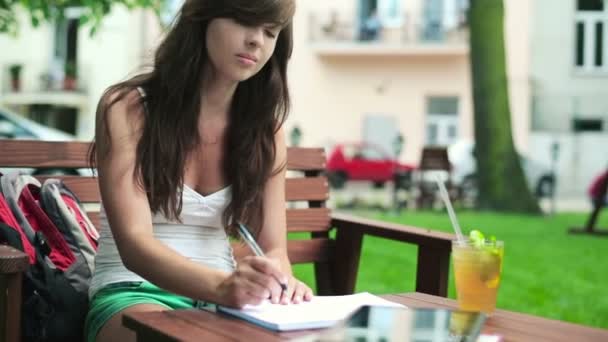 Estudiante escribiendo en cuaderno en el parque de la ciudad — Vídeo de stock