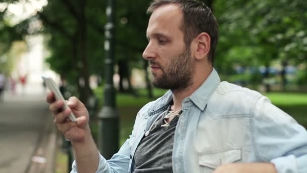 Man met smartphone zitten — Stockvideo