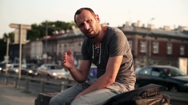 Sad young man sitting by the street — Stock Video