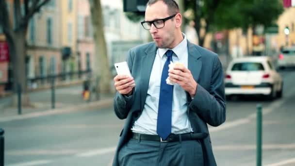 Homme d'affaires avec smartphone manger sandwich — Video