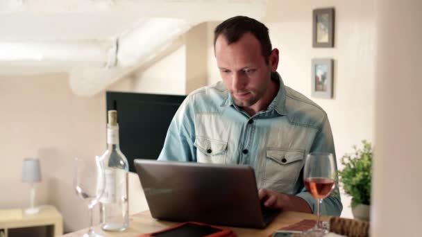 Mann arbeitet am Laptop und trinkt Wein — Stockvideo