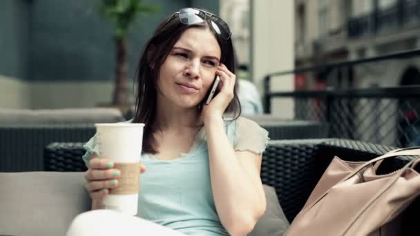 Женщина разговаривает по телефону и пьет кофе — стоковое видео
