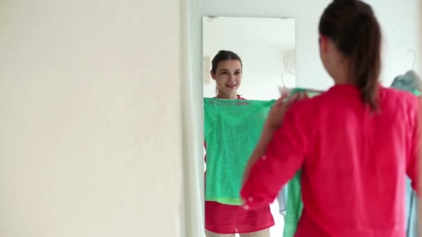 Женщина пробует разноцветные рубашки — стоковое видео