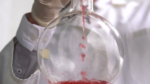 Учёный заливает химикаты во фляжку — стоковое видео