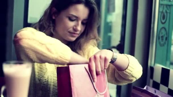 Mujer revisando ropa nueva en la cafetería — Vídeos de Stock