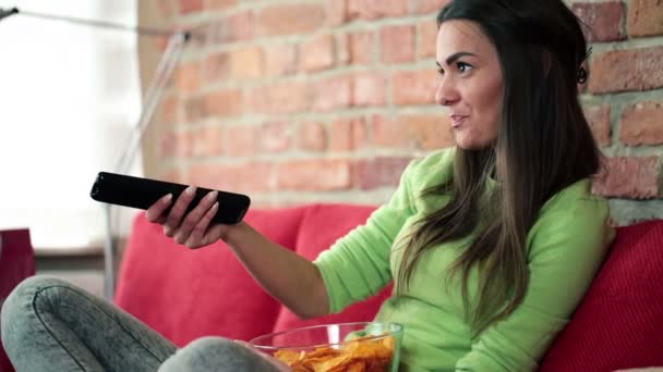 Mujer comiendo patatas fritas y viendo la televisión — Vídeos de Stock