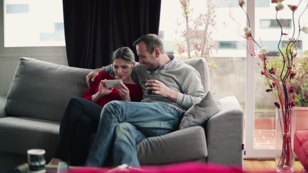 Paar mit Smartphone sitzt auf Sofa — Stockvideo