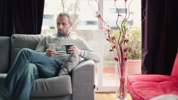 Man drinking tea and using smartphone — Stock Video