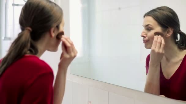 Vrouw toepassing van make-up op gezicht met borstel — Stockvideo