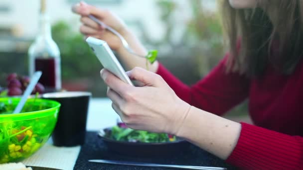 Γυναίκα τρώει μεσημεριανό γεύμα και χρήση smartphone — Αρχείο Βίντεο