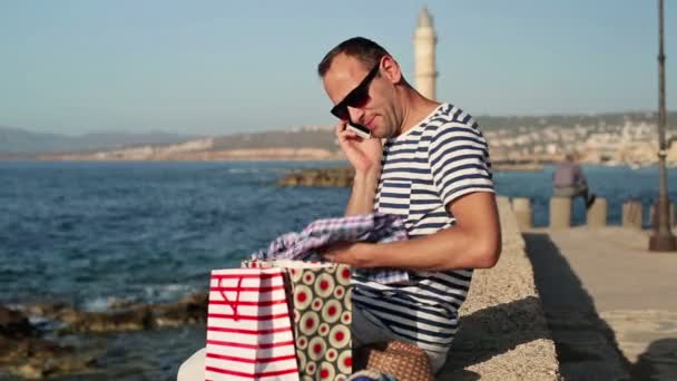 Hombre hablando por celular y revisando bolsas — Vídeo de stock