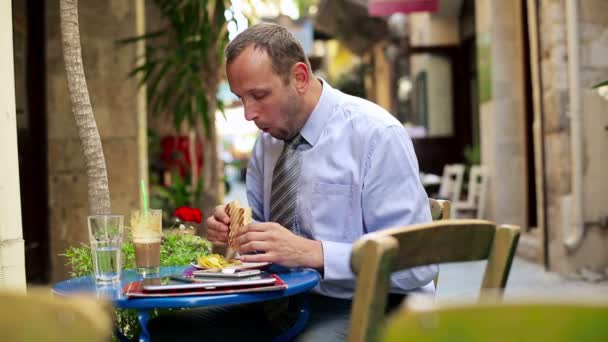 Businessman eating sandwich in cafe — Stock Video