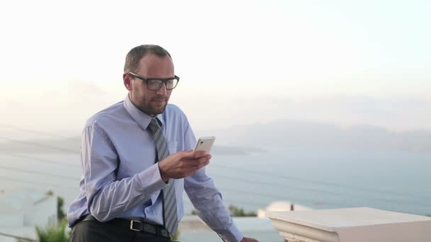 Businessman with smartphone on terrace — Stock Video