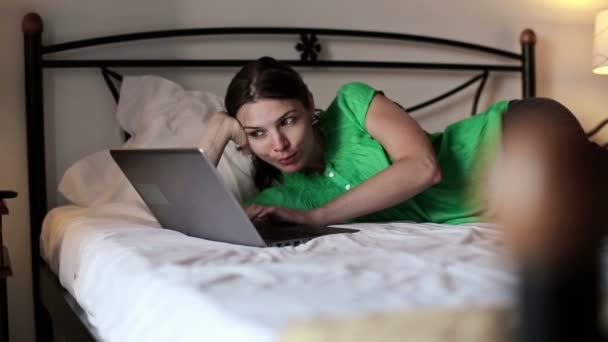 Mujer en la cama viendo en el ordenador portátil — Vídeo de stock