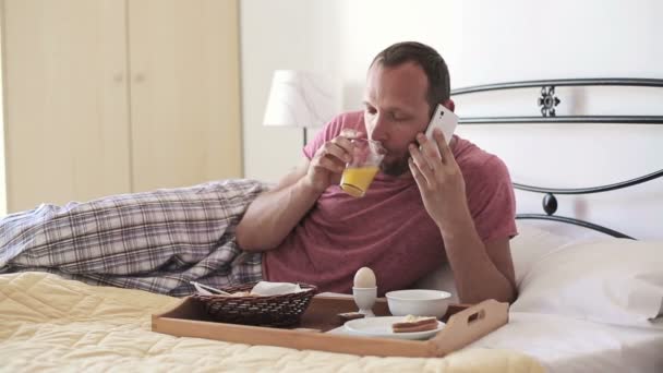 Mannen i sängen talar i mobiltelefon — Stockvideo