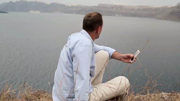 Homme utilisant un smartphone près de la mer — Video