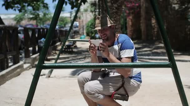 Людина на гойдалках зі смартфоном — стокове відео