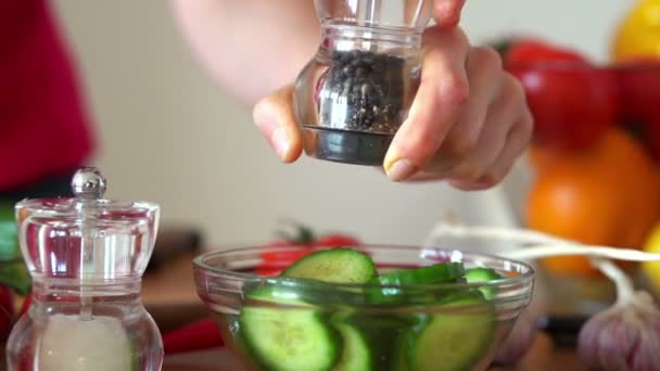 Strooi peper op komkommer salade — Stockvideo
