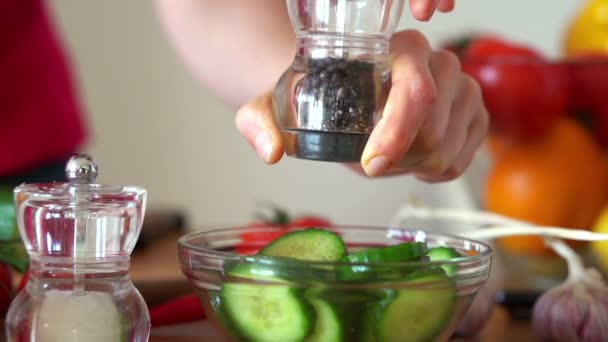 Strooi peper op komkommer salade — Stockvideo
