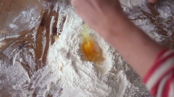 Hands cracking egg over flour — Stock Video