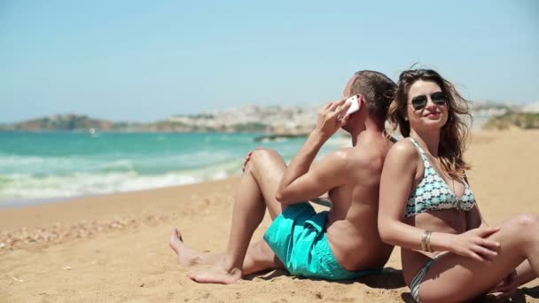 Happy couple talking on cellphone on beach — Stock Video