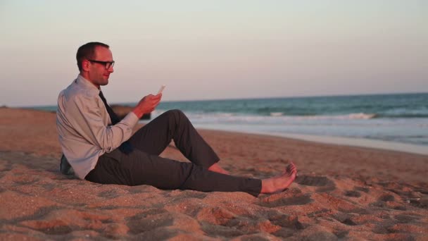 Homme d'affaires utilisant un smartphone sur la plage — Video