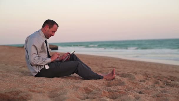 Empresario en tableta ordenador en la playa — Vídeo de stock