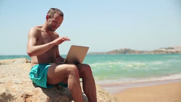 Hombre terminar el trabajo en el ordenador portátil en la playa — Vídeo de stock