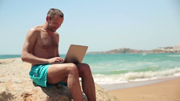 Mann arbeitet am Strand am Laptop — Stockvideo