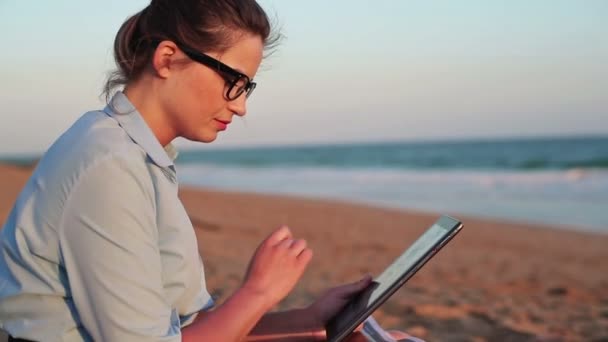 Kobieta pracuje na tabletki na plaży — Wideo stockowe