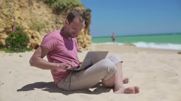 El hombre que trabaja en el portátil en la playa — Vídeo de stock