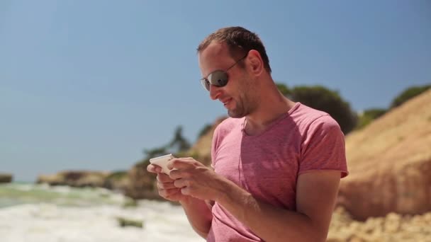 Hombre usando teléfono inteligente en la playa — Vídeos de Stock