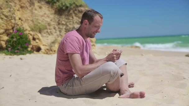 Hombre usando teléfono inteligente en la playa — Vídeos de Stock