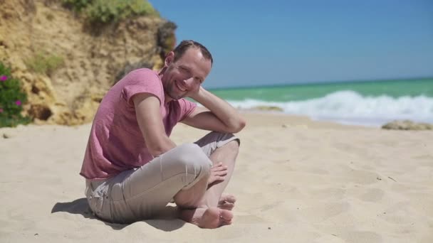 Mann sitzt am Strand — Stockvideo
