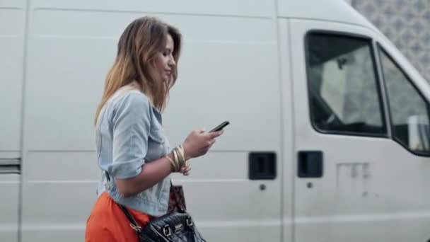 Vrouw met smartphone wandelen in de stad — Stockvideo