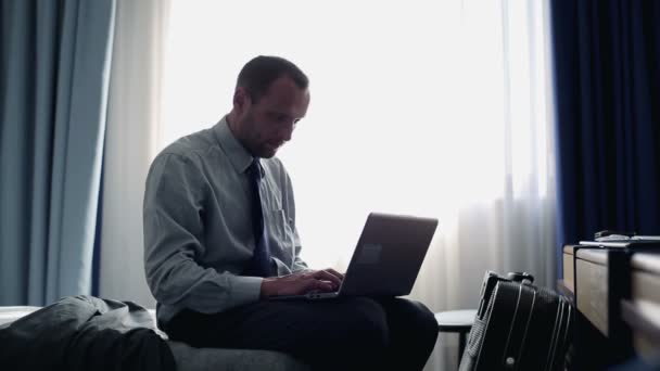 Otel odasında dizüstü bilgisayarda çalışan bir iş adamı. — Stok video