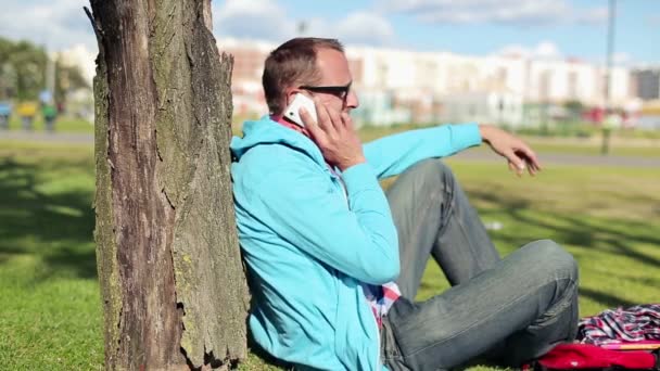 Student talar i mobiltelefon i park — Stockvideo