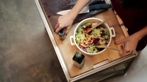 Frau fügt Gewürze hinzu und verkostet Salat — Stockvideo