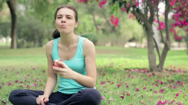 Sportswoman manger de la pomme dans le parc — Video