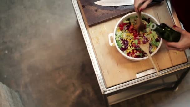 Frau gießt Olivenöl in Salat — Stockvideo