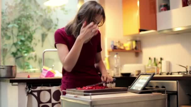 Mujer rebanando tomate y buscando receta — Vídeo de stock