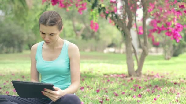 Sportswoman using tablet in park — Stock Video